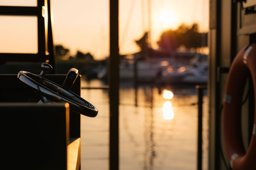 The boat's helm silhouetted against the sun setting over the marina