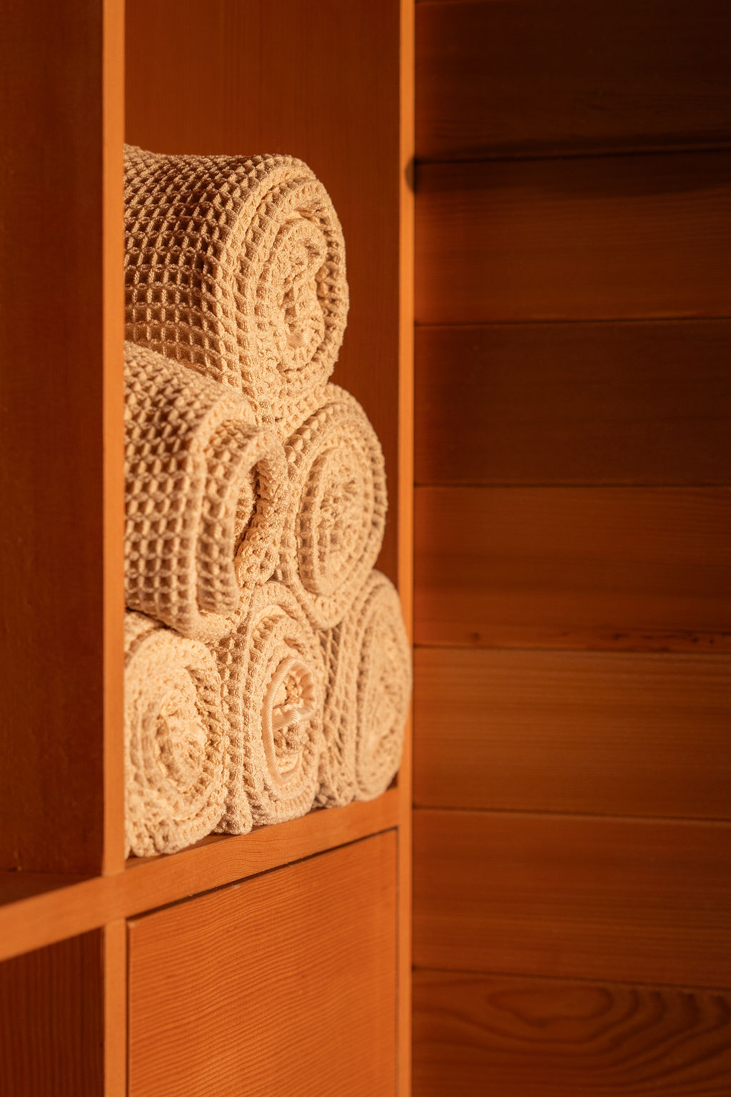 Waffle-knit towels rolled and stacked in a cedar cubby