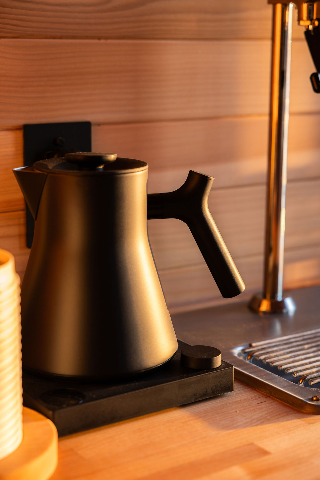 Matte black kettle on the cedar tea counter in warm evening light